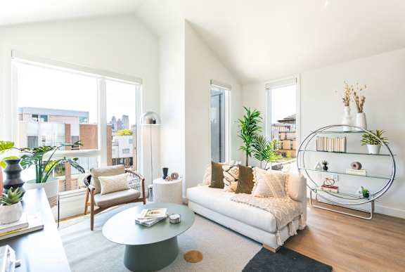 A living room with a white couch and a glass coffee table.