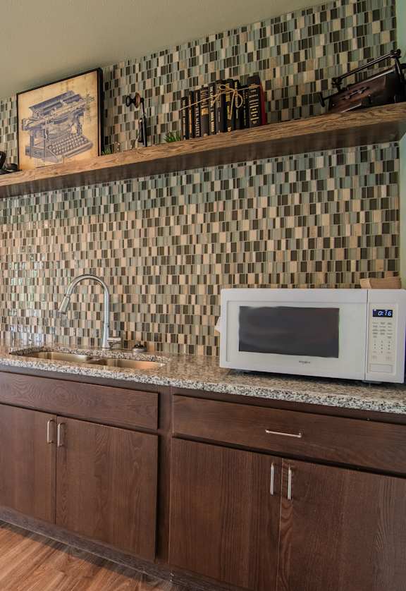 A kitchen with a white refrigerator, brown cabinets, and a black and white checkered backsplash.