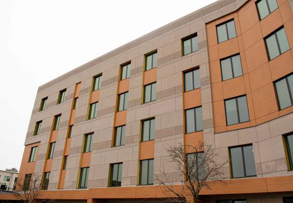 A tall building with orange and beige panels and windows.