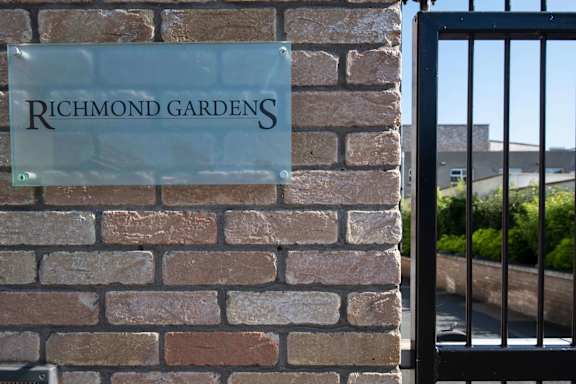 a sign that reads richmond gardens on a brick wall