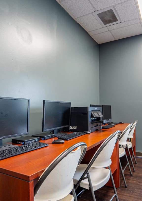 a computer room with desks and chairs and a computer on a table