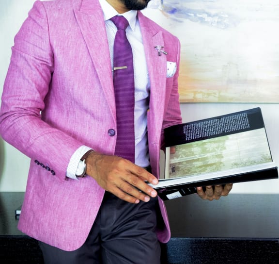 a man in a pink suit holding a book