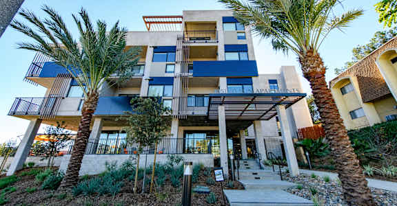 A modern building with a blue and white facade surrounded by palm trees.