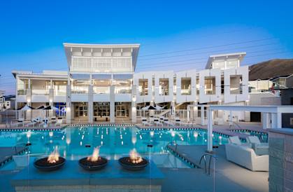 A large white building with a pool in front of it.