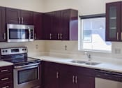 Thumbnail 2 of 5 - A kitchen with dark brown cabinets and a stainless steel oven.