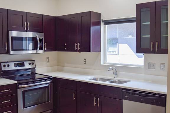 A kitchen with dark brown cabinets and a stainless steel oven.