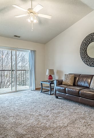 a living room with leather couches and a ceiling fan