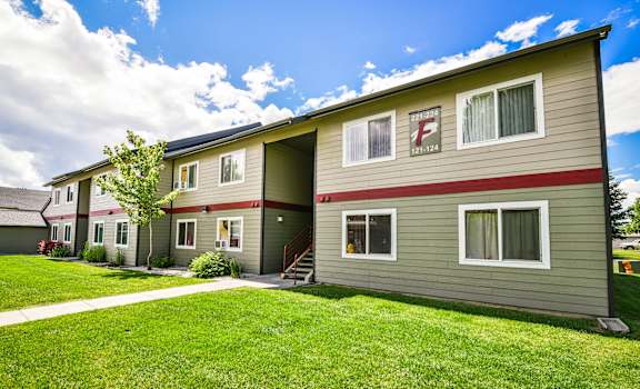 a green and red apartment building with green grass and a sidewalk