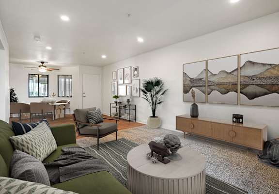 A living room with a green couch, a coffee table, and a painting on the wall.