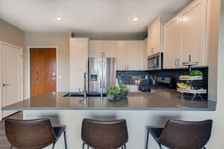 Premium kitchen featuring dark quartz countertops, white cabinetry and stainless-steel appliances at Ascend at Woodbury best new apartments Woodbury MN 55129