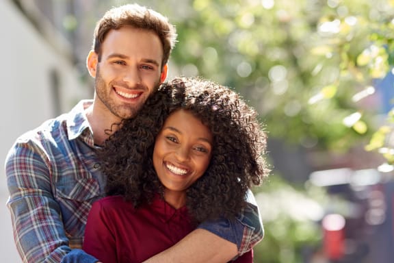 a man and a woman smiling at the camera with their arms around each other