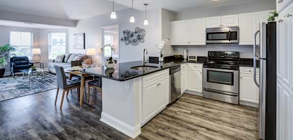an open kitchen and living room with a dining room table and a refrigerator