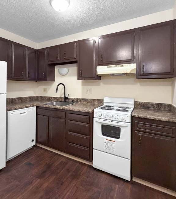 A kitchen with brown cabinets and a white fridge.