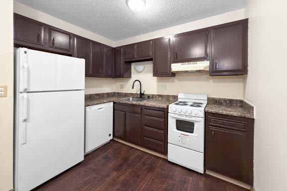 A kitchen with brown cabinets and a white fridge.