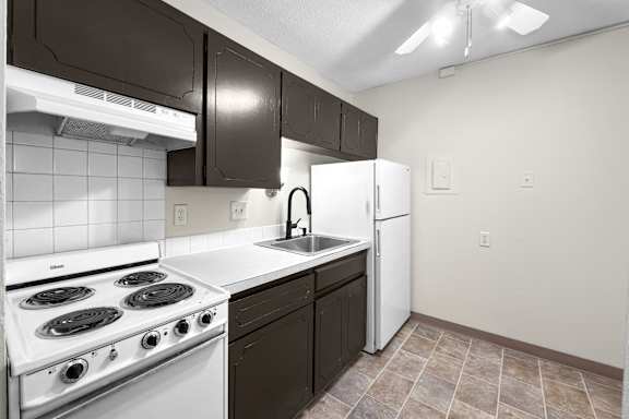 A kitchen with a white stove top oven and black cabinets.