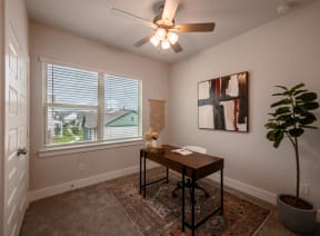 an office with a large window and a ceiling fan