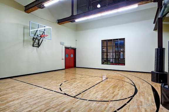 the inside of an empty gym with a basketball court and a red door
