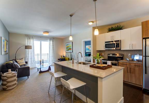 A kitchen with a white countertop and a dining table with chairs.