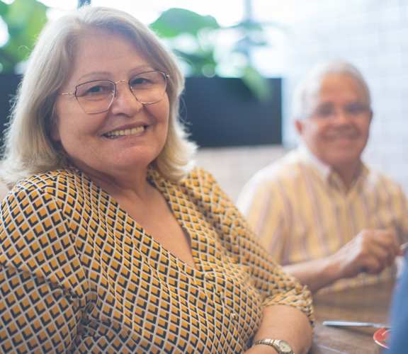 a woman sitting at a table with a man in the background
