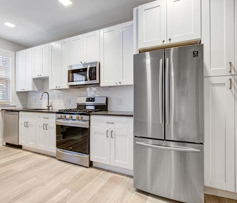 a white kitchen with stainless steel appliances and white cabinets