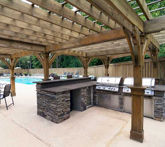 A wooden pergola over a pool with chairs and a barbecue. at Westbury Creek, Augusta, GA, 30909