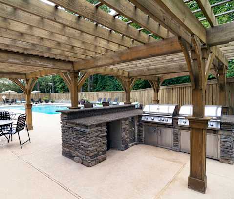 A wooden pergola over a pool with chairs and a barbecue. at Westbury Creek, Augusta