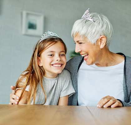 A grandmother wrapping her arm around her granddaughter sitting at a table