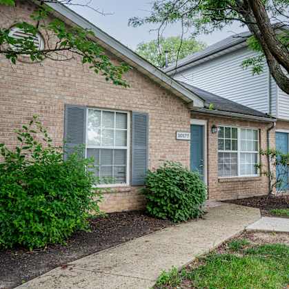 A house with a blue door and a tree in front.