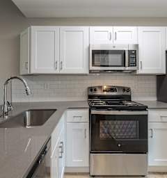 A modern kitchen with a stove, sink, and refrigerator.