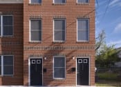 Thumbnail 2 of 4 - a red brick building with black doors and windows
