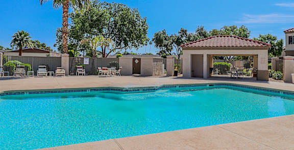 A pool surrounded by palm trees and a building.