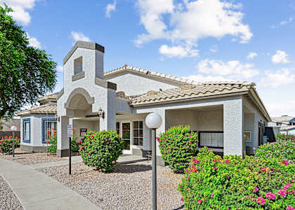 an exterior view of a house with bushes and a sidewalk