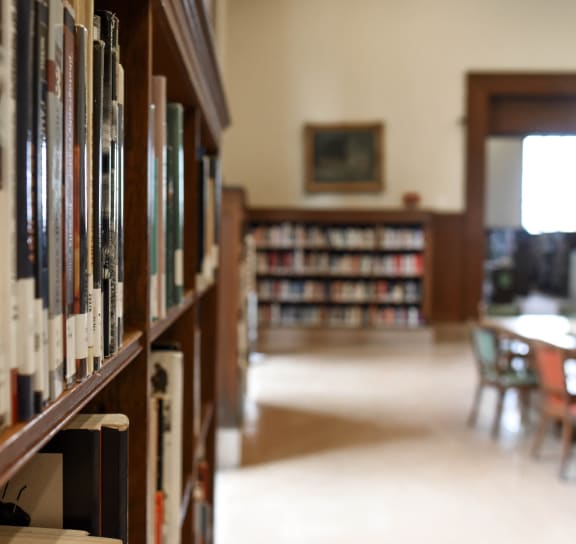 a view of the library with bookshelves and a dining room in the background