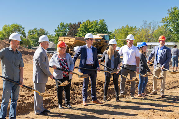 a group of people in hard hats standing in a field with shovels