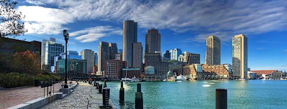 A city skyline is seen from a waterfront walkway.
