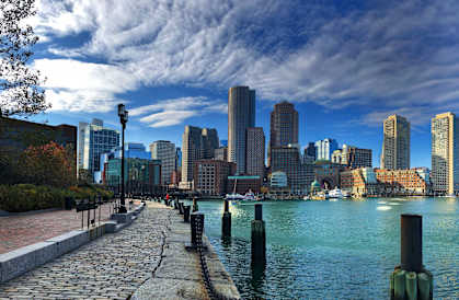 A city skyline is seen from a waterfront walkway.