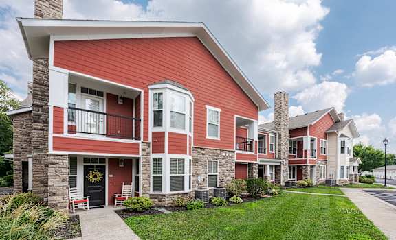 a row of red apartment buildings with grass and a sidewalk