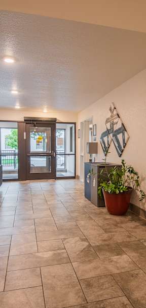 A spacious lobby with a couch, potted plant, and a painting on the wall.