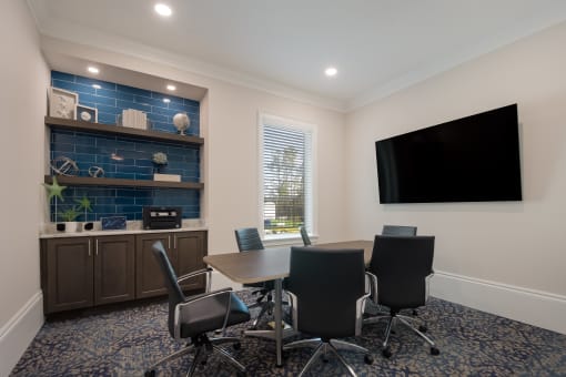 a meeting room with a table and chairs and a flat screen tv