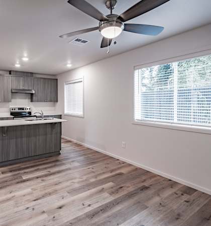 A modern kitchen with wooden floors and a ceiling fan.