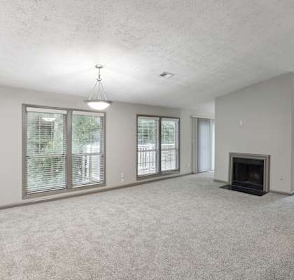 A spacious living room with a fireplace and large windows.