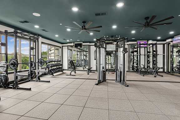 A spacious gym with a variety of equipment and a ceiling fan.
