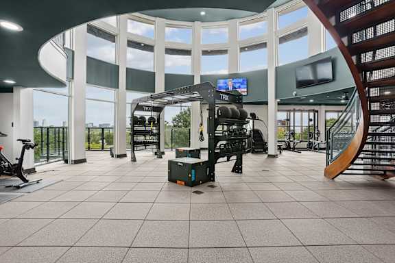 A spacious gym with a variety of equipment and a bench for resting.