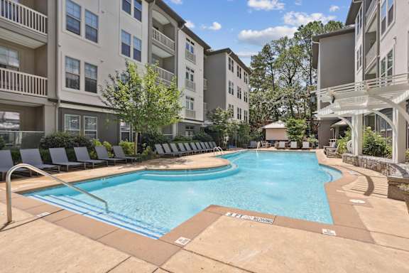 A large swimming pool in front of a multi-story apartment building.