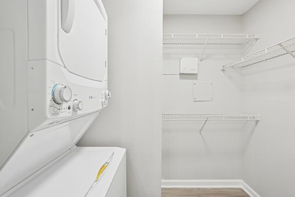 A white dryer is on the left of a white wall.