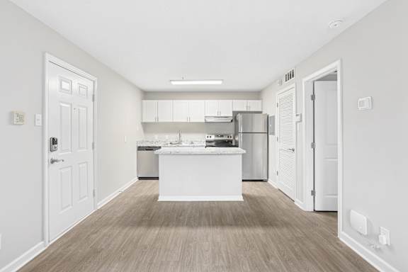 A kitchen with white cabinets and a white island in the middle.