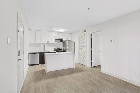 A kitchen with a white island and wooden floors.