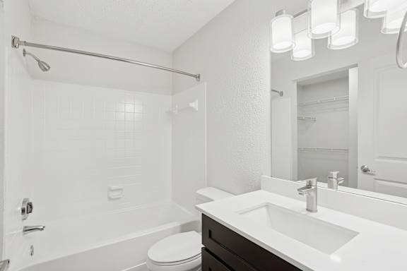 A white bathroom with a toilet, sink, and shower.