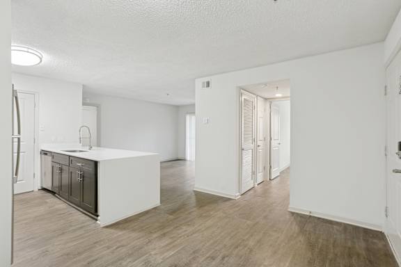 A kitchen with a white countertop and wooden floors.