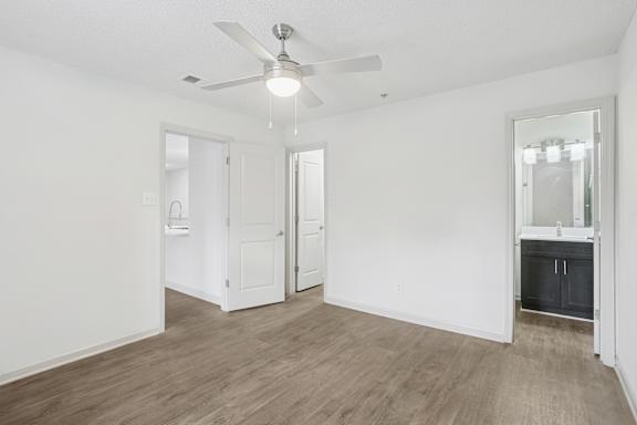 A room with a ceiling fan and wooden flooring.